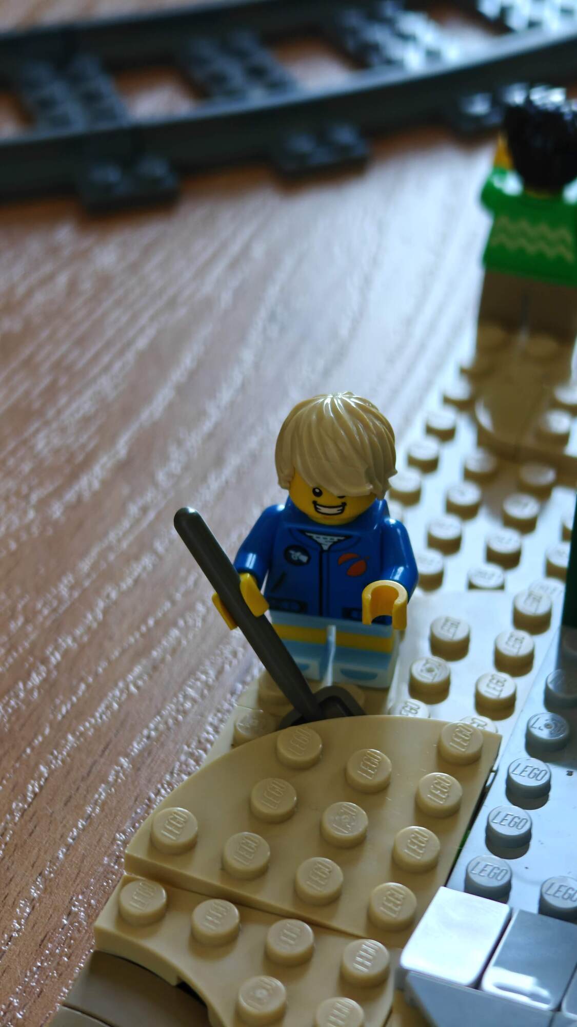 A minifigure digs in the sand with a shovel
