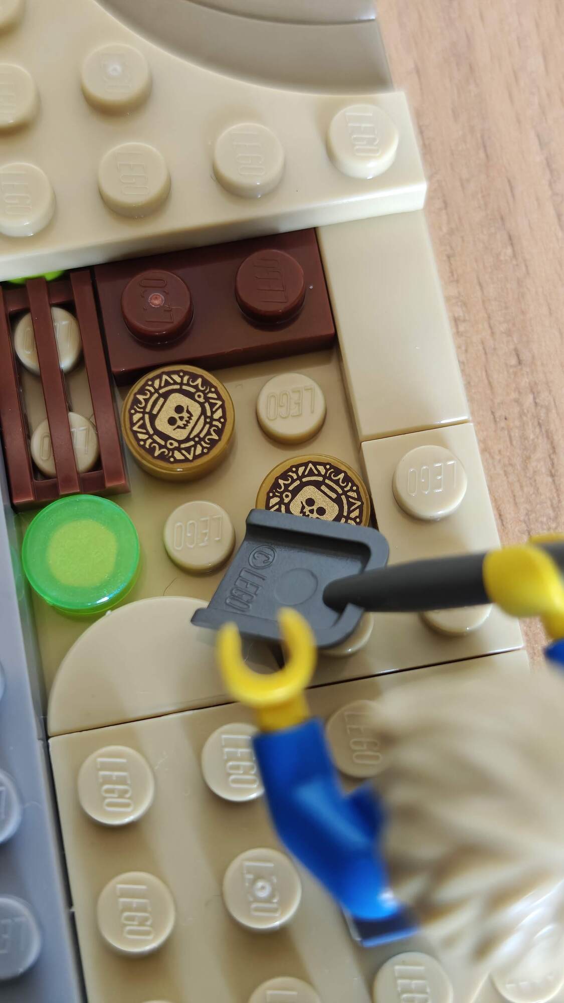 A minifigure finds several gold coins in the sand with a shovel