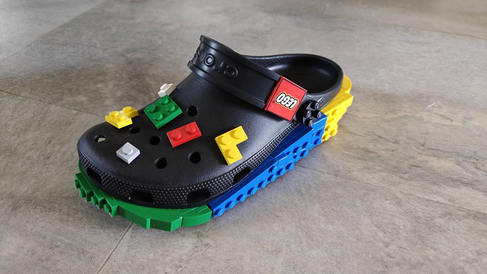 Front view of one black LEGO® Croc with colored Jibbitz