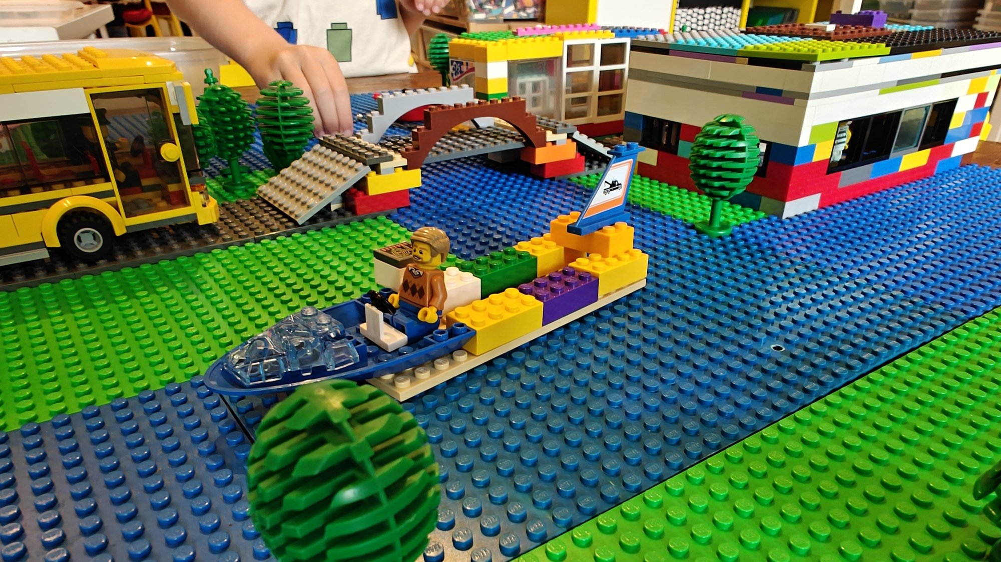 Un bateau construit avec une minifig, tandis qu'un bus veut traverser le pont en arrière-plan