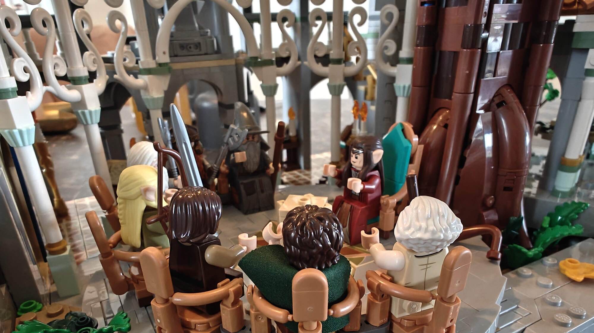 Todos os membros estão sentados na grande mesa de conferências em Rivendell em suas próprias cadeiras ouvindo o Rei Elrond