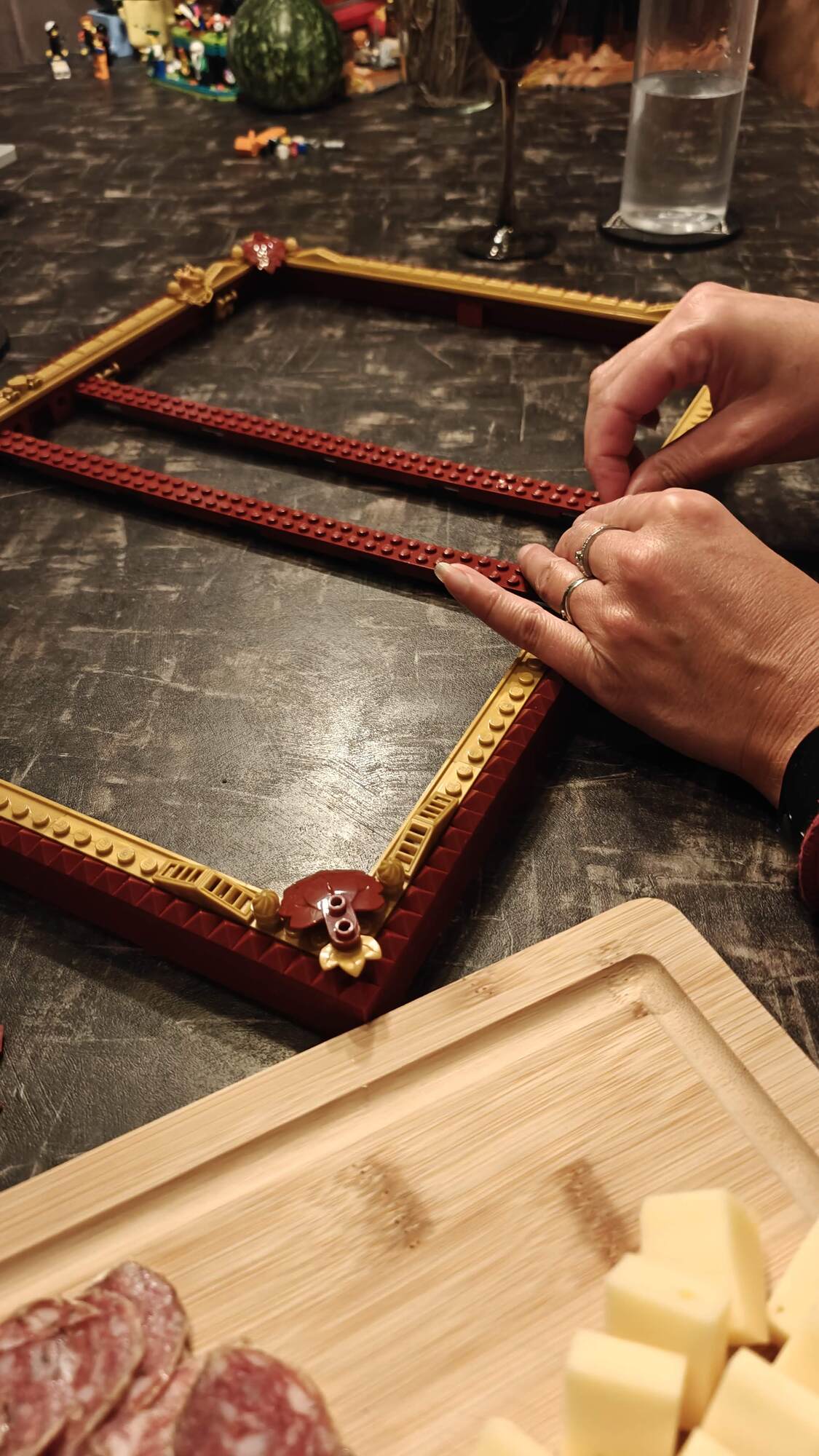Tabua com salsicha e queijo atrás das mãos da minha esposa construindo