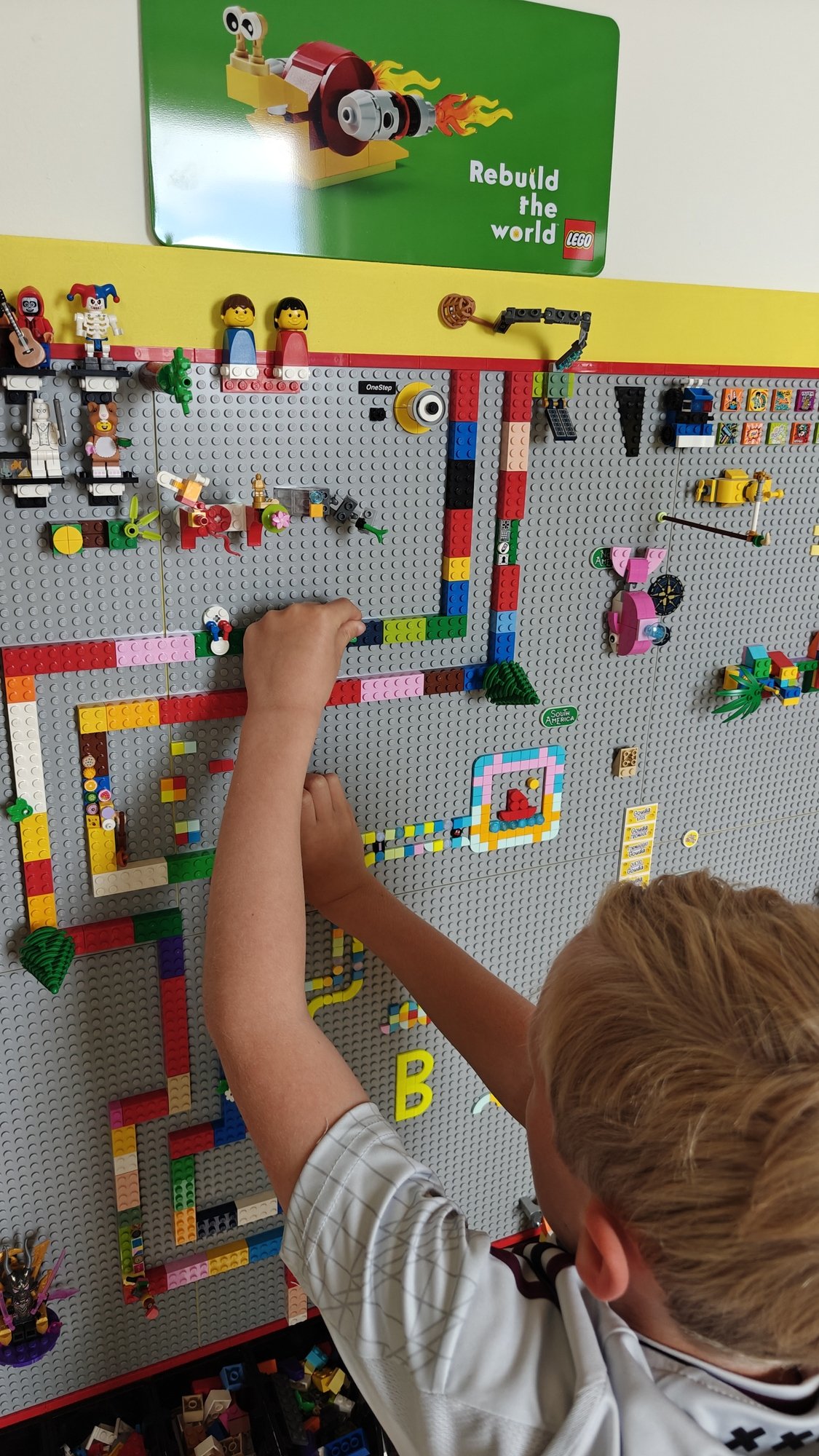 Mio figlio che attacca mattoncini al muro mentre costruisce il percorso