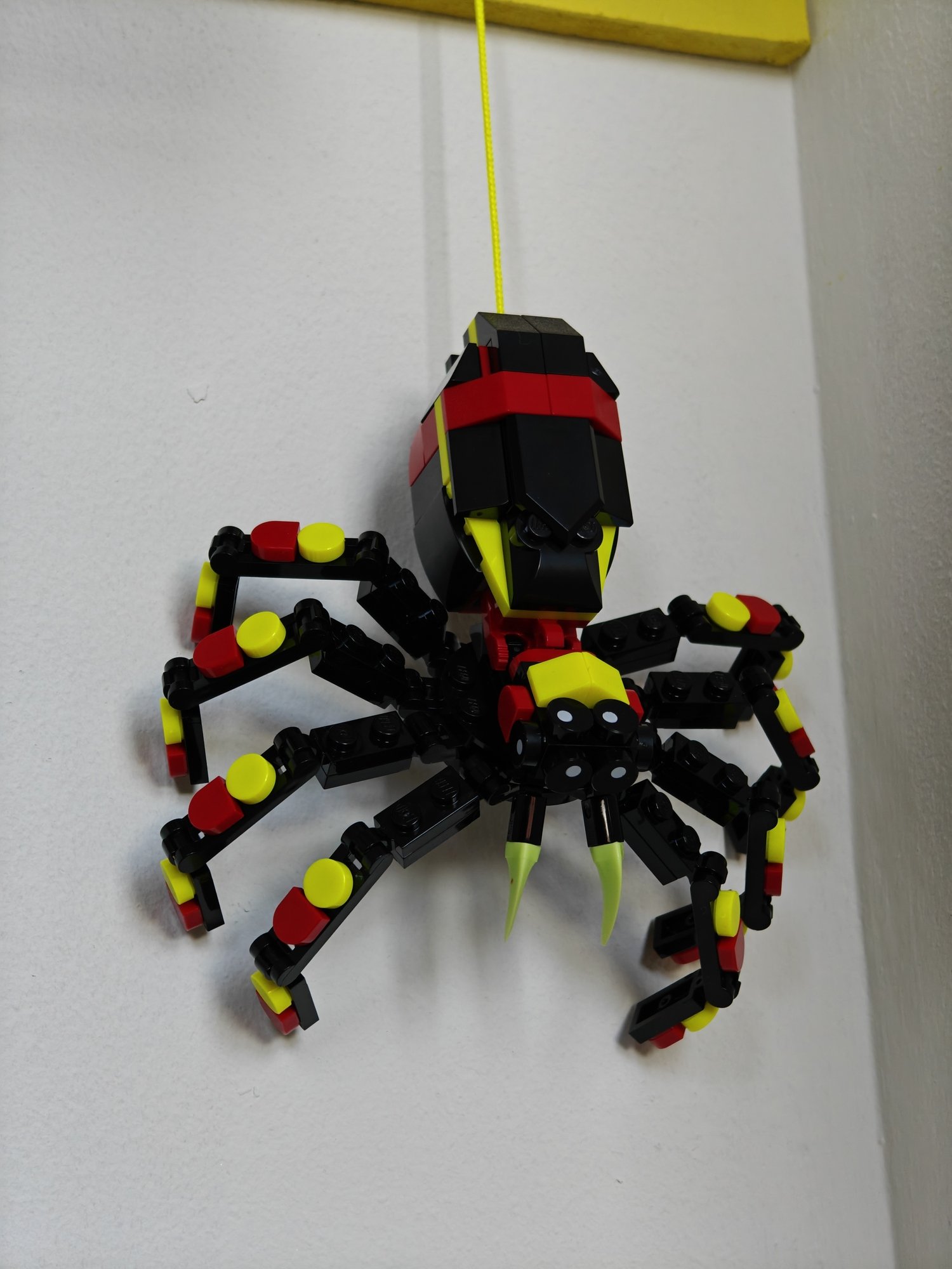 Zoomed-in view of the spider hanging from the LEGO® Brick Wall on a string