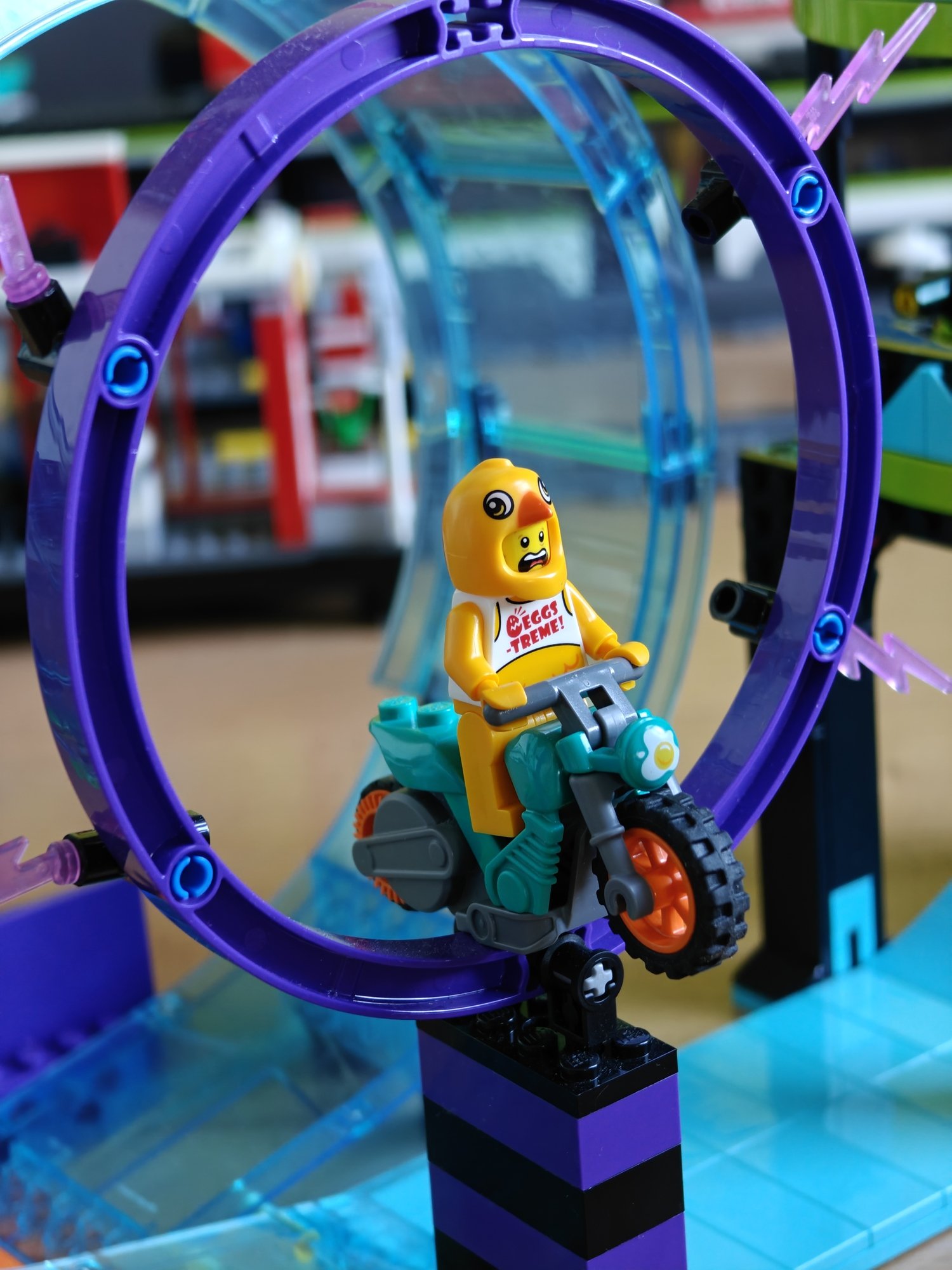 A frightened-looking minifig stuck on the bike mid-stunt inside the ring